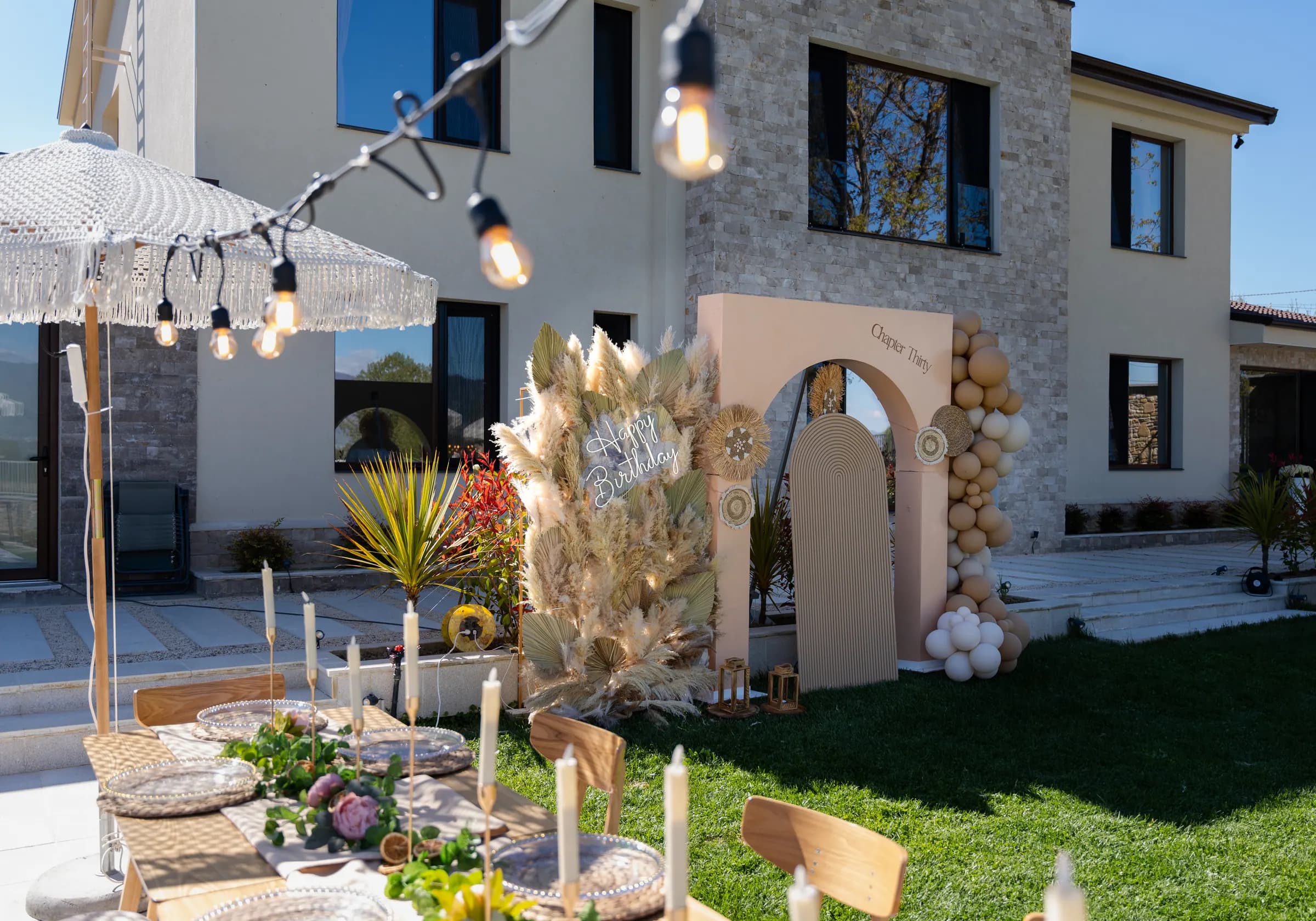 Tavolinë e gjatë festive në kopsht me pampas, qirinj dhe ombrella boho – My Dream, Korçë Tavolinë e gjatë festive në kopsht me pampas, qirinj dhe ombrella boho